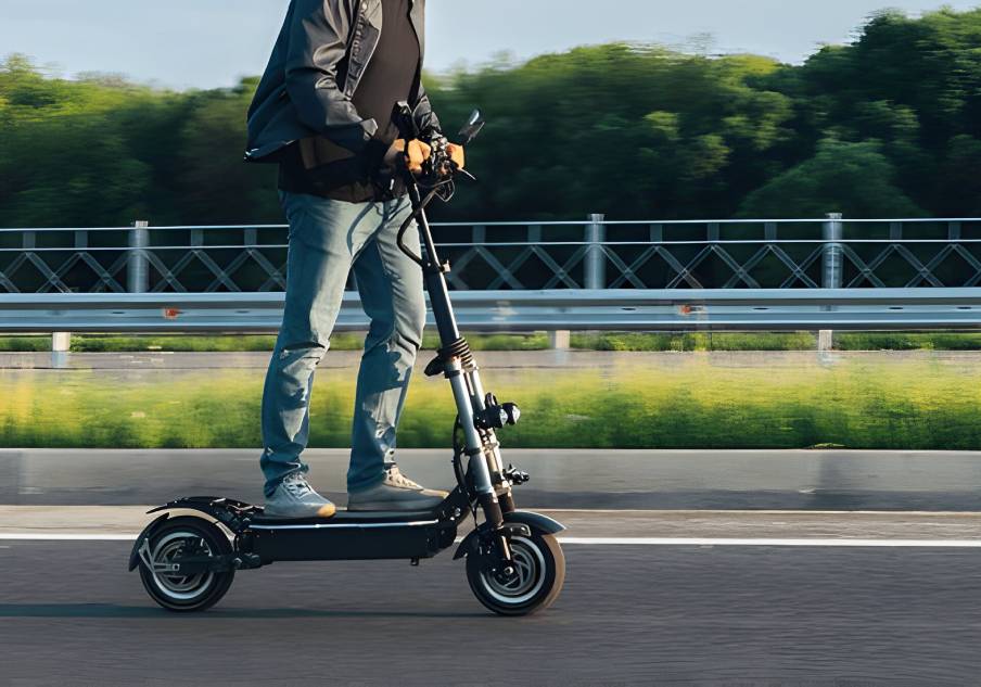 A képen egy férfi gurul az elektromos rollerjával